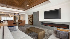 Uma área de estar moderna com lareira, assentos confortáveis e uma grande TV de tela plana na parede.