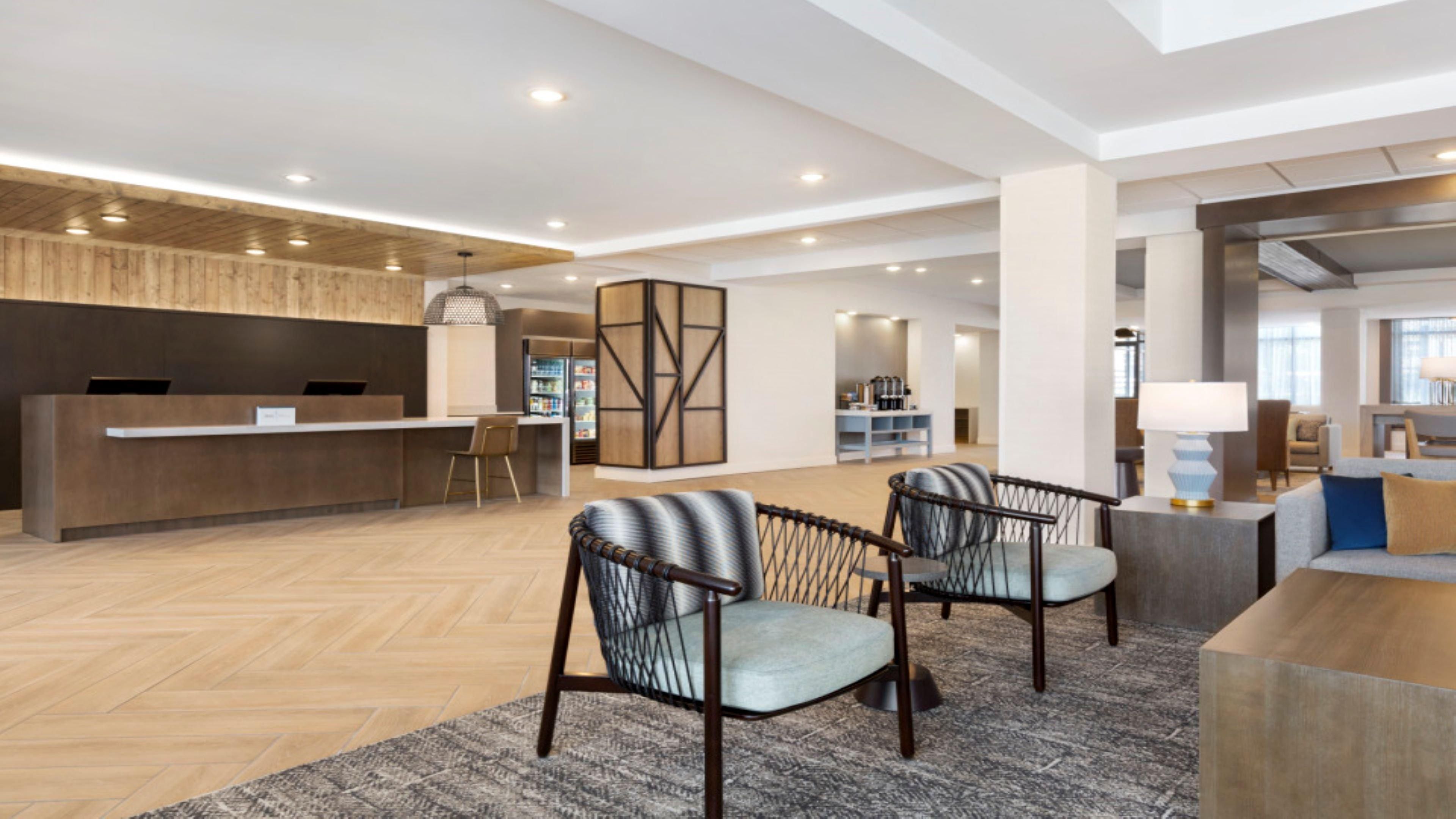 A spacious lobby with a reception desk, seating area, and a coffee bar.