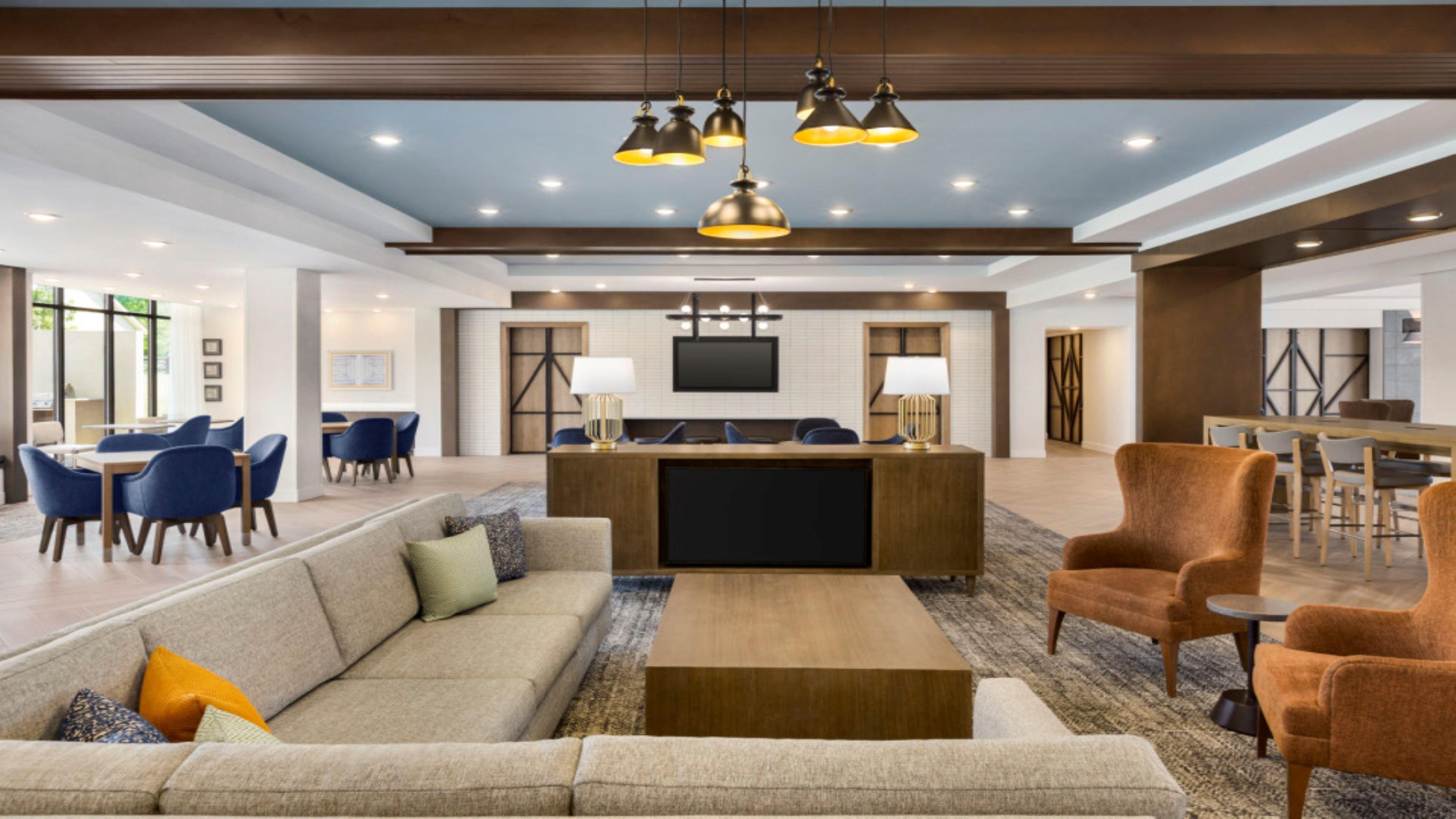 Eine großzügige Lobby mit einer Rezeption, Sofas und einem Essbereich.