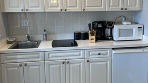 A modern kitchen with white cabinets, a built-in microwave, a coffee maker, and a dishwasher.
