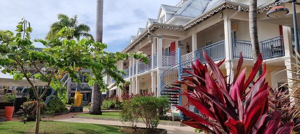 A multi-story building with balconies, a spiral staircase, and a well-maintained garden with various plants.
