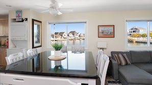 Una cocina moderna con comedor, ventilador de techo y amplios ventanales con vista al agua.