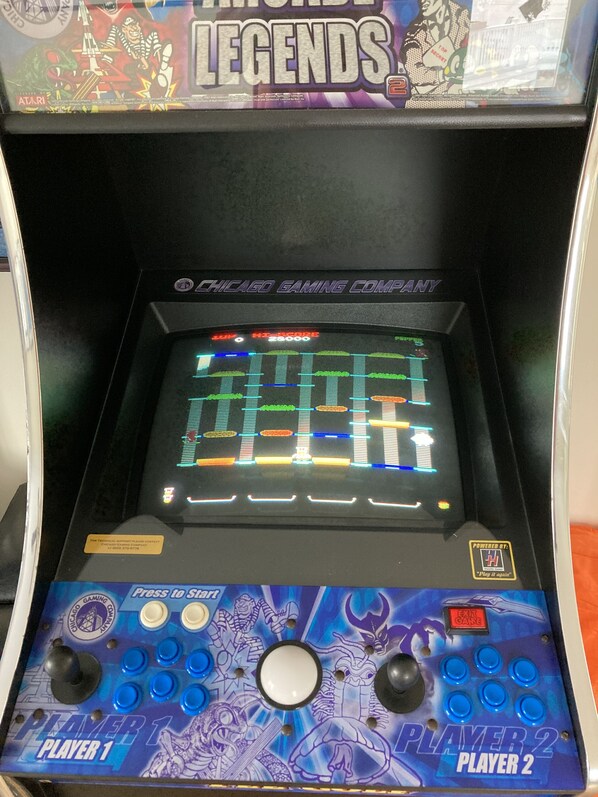 An arcade machine with a score display, two joystick controls, and a "Press to Start" button.