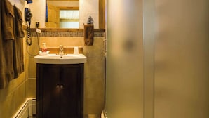 Un baño con lavamanos, espejo, toallero y zona de ducha.