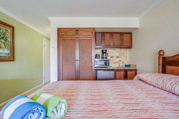 Una habitación de hotel con cama, kitchenette pequeño y baño.