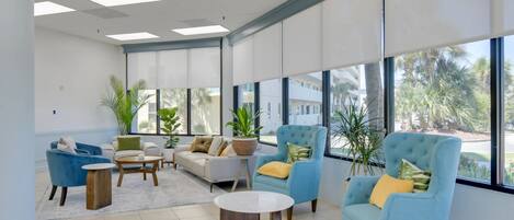A spacious lounge area with large windows, comfortable seating, and potted plants.