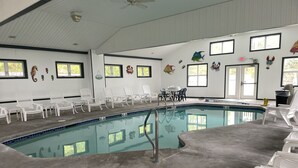 Una piscina interior amb cadires blanques i un sòl de rajola.
