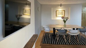 Ein moderner Essbereich mit einem Holztisch, grauen Stühlen und einem schwarz-weißen Streifen Teppich.
