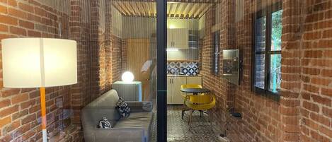 Una habitación acogedora con pared de ladrillo, un sofá, una mesita y una silla amarilla.