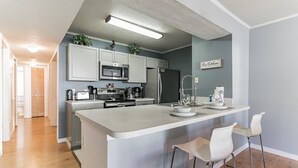 A modern kitchen with white cabinets, stainless steel appliances, and a central island with bar stools.