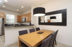 Una cocina moderna con armarios de madera, encimera negra y comedor con mesa y sillas de madera.