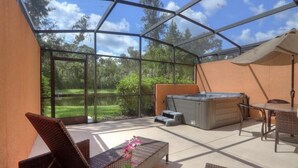 Un espace extérieur abrité comprenant un jacuzzi, des sièges et une vue sur un lac.
