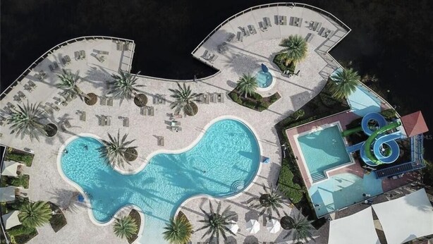 Vue aérienne d’un complexe hôtelier doté d’une grande piscine, de chaises longues et d’un toboggan aquatique.