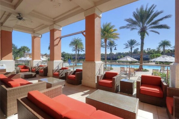 Relax in a serene outdoor lounge area surrounded by palm trees and a sparkling pool.