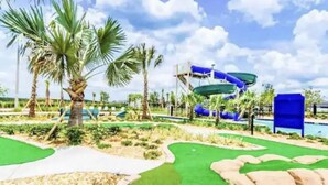 A water park with palm trees, a water slide, and a pool area. - Storey Lake Resort, Private Pool, Near Famous Attractions!! (Kissimmee)