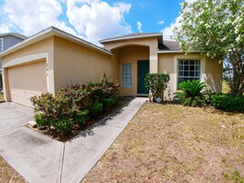A residential house with a garage, a front door, and a driveway leading to the garage.