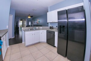 A modern kitchen with white cabinets, a stainless steel refrigerator, and a dishwasher.