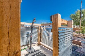 A covered outdoor area with a metal gate, wooden posts, and a metal roof structure. - Topo House II: Fenced Yard & Fire Pit Oasis (Fruita)