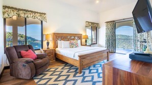 Une chambre à coucher avec un lit, un fauteuil inclinable, une télévision et un balcon avec vue.