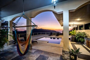 A rooftop pool area with a hammock, outdoor seating, and a view of the sunset over mountains. - Mount view  Villa Jaco Bijagual (Carara)