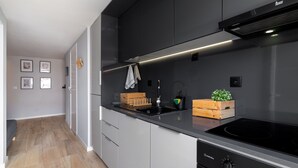 A modern kitchen with grey cabinets, a black countertop, and a built-in stove.