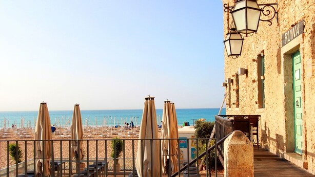 A beachside restaurant with outdoor seating and a view of the sea.