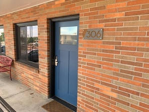 A brick building with a blue door and a window. - Apartment 306 - A kitchenette with everything you (Rapid City)