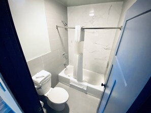A bathroom with a toilet, a bathtub, and a shower. - Apartment 306 - A kitchenette with everything you (Rapid City)