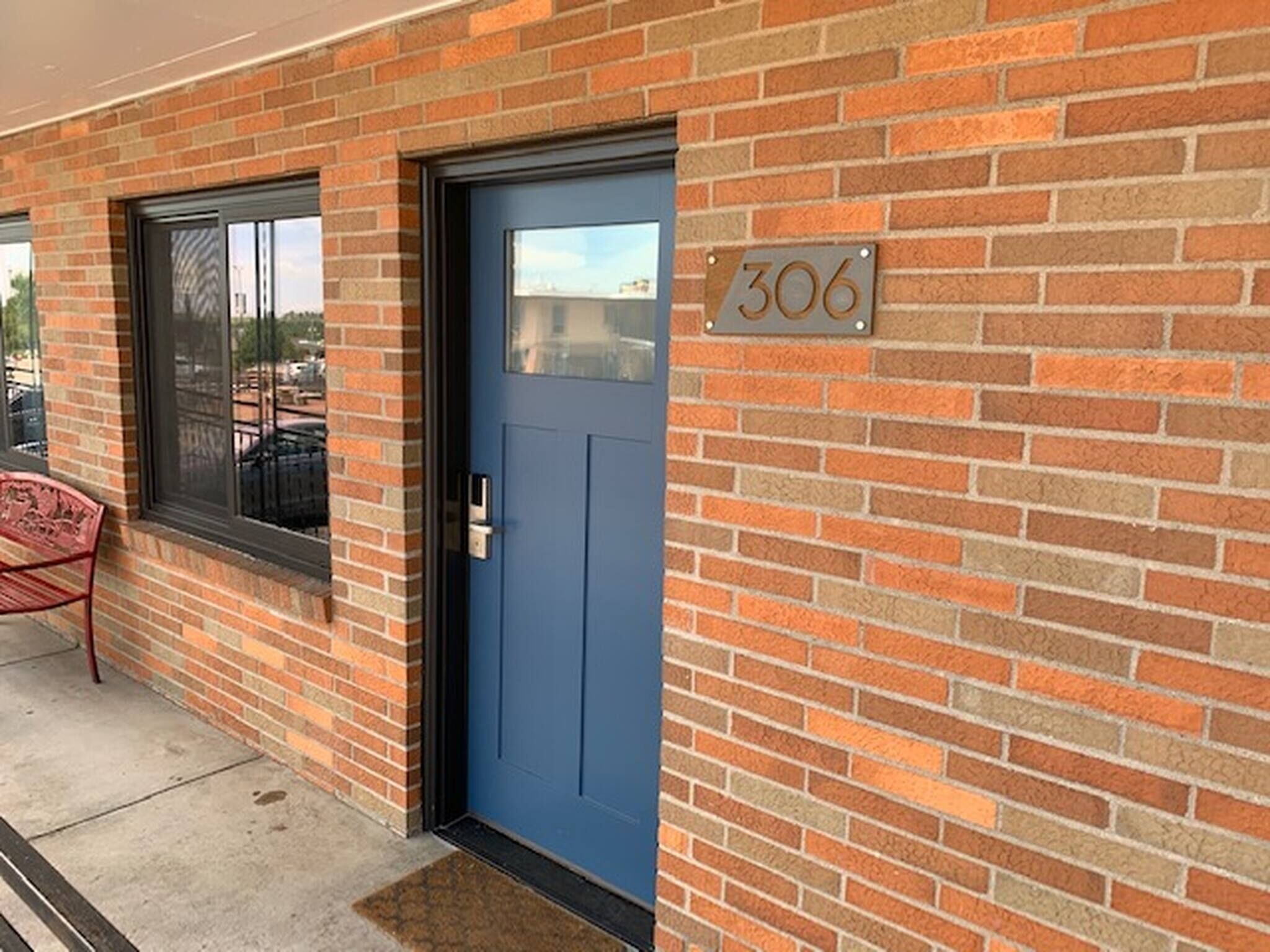 A brick building with a blue door and a window.