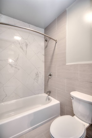 A bathroom with a bathtub, toilet, and a shower area.