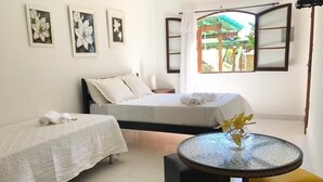 A room with two beds, a round glass table, and a yellow chair. - Pousada Sonho Meu (Itanhandu)