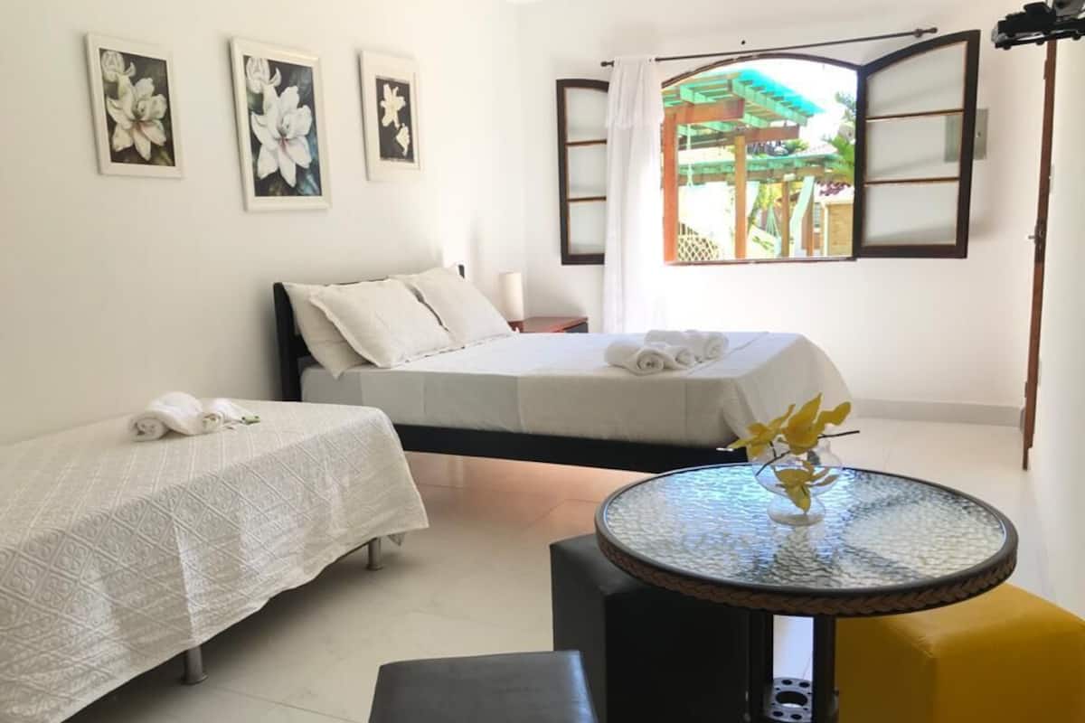 Una habitación con dos camas, una mesa redonda de vidrio y una silla amarilla.