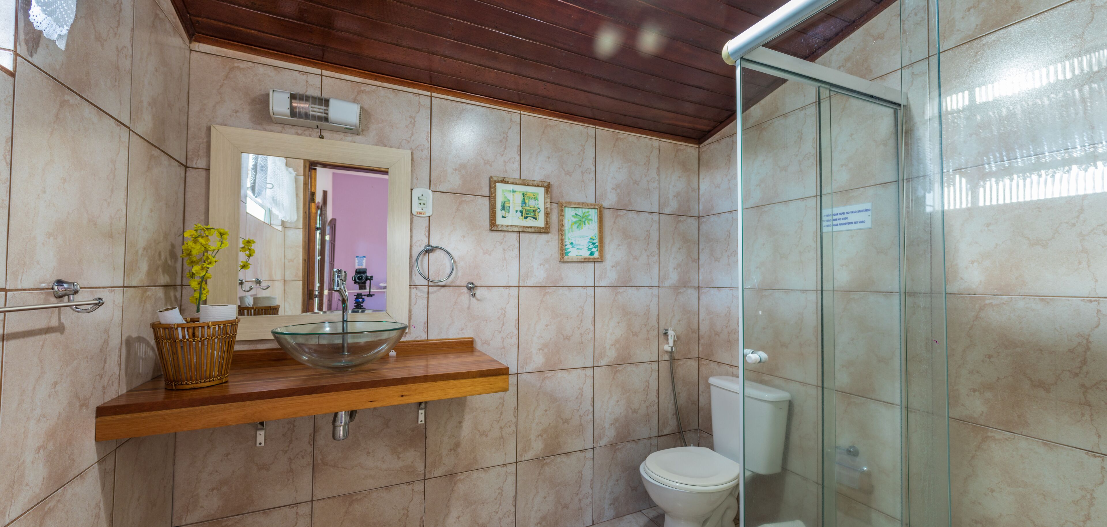 Un baño con lavamanos de vidrio, encimera de madera y cabina de ducha de cristal.