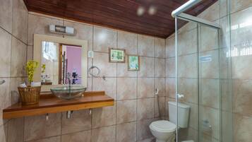 A bathroom with a glass sink, wooden countertop, and a glass shower enclosure.