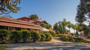 A hotel with a red facade, a gravel driveway, and tropical landscaping. - Pousada Sonho Meu (Itanhandu)