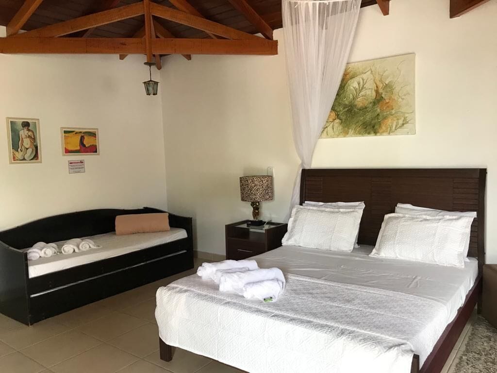 Ein Schlafzimmer mit Bett, Sofa, Nachttisch und Kunstwerk an der Wand.