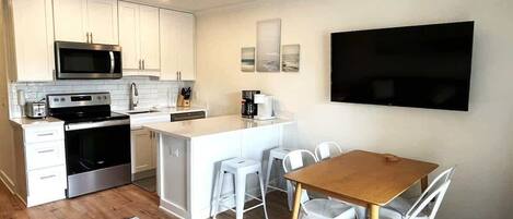 A modern kitchen with white cabinetry, a built-in microwave, and a central island with bar stools.