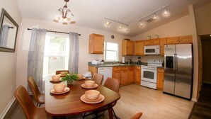 Una cocina moderna con armarios de madera, un refrigerador de acero inoxidable y un comedor con mesa y sillas de madera.