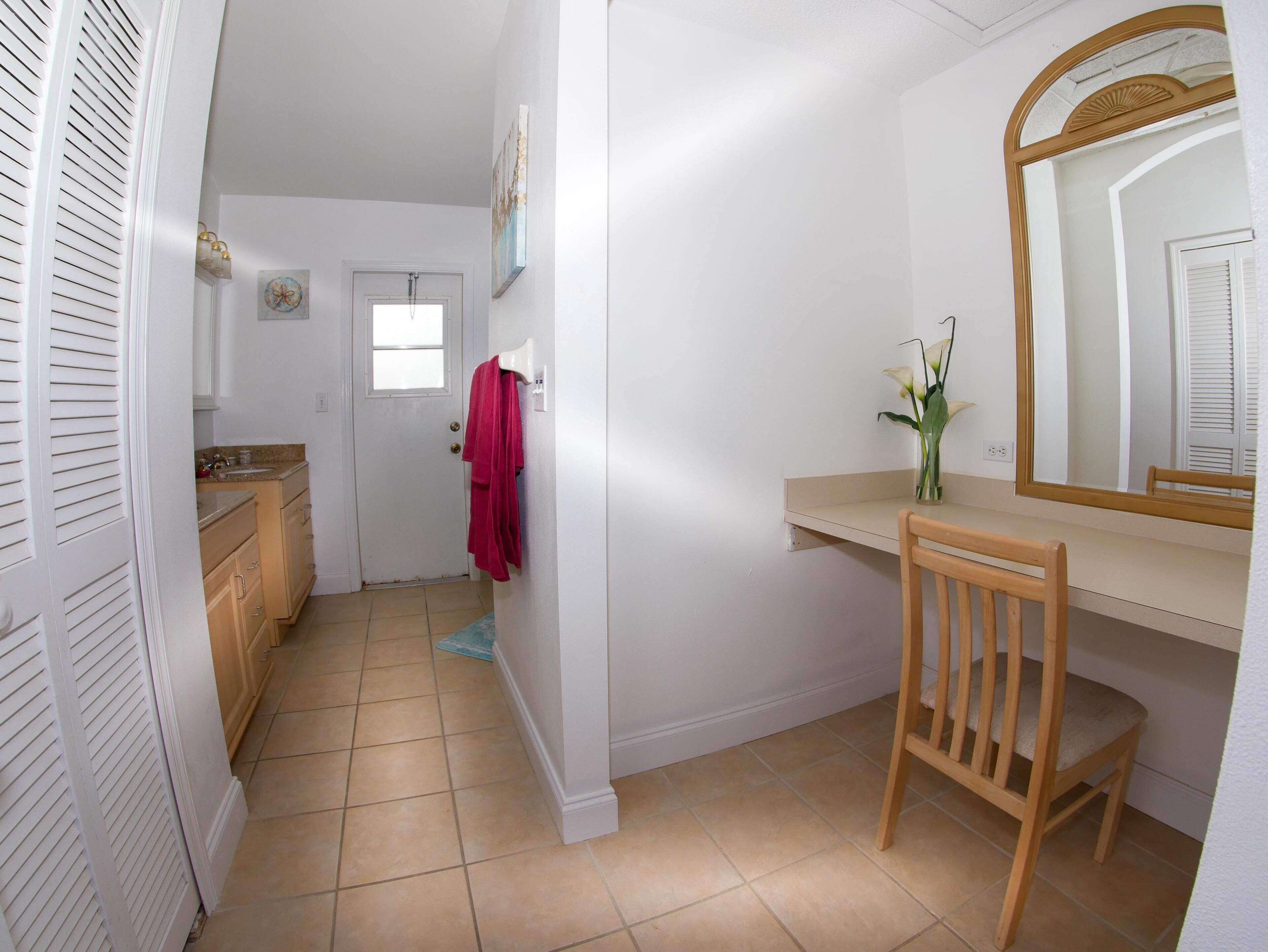 A bathroom with a wooden chair, a mirror, a sink, and a towel rack.