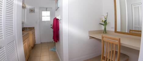 A bathroom with a wooden chair, a mirror, a sink, and a towel rack.