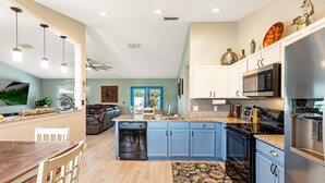 A modern kitchen with blue cabinets, stainless steel appliances, and a dining area with a wooden table and chairs. - Private Pool House, Near all Famous Attractions!!! (Kissimmee)