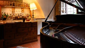 A piano in a room with a bar area, wooden cabinets, and a window. - borgo antico resort diffuso (Bassano in Teverina)