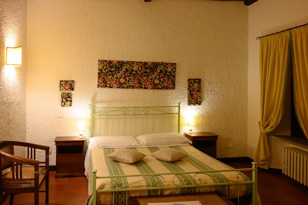 A bedroom with a bed, two bedside tables, a chair, and a window with curtains.