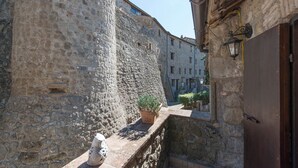 A narrow stone corridor with a potted plant and a stone statue. - borgo antico resort diffuso (Bassano in Teverina)
