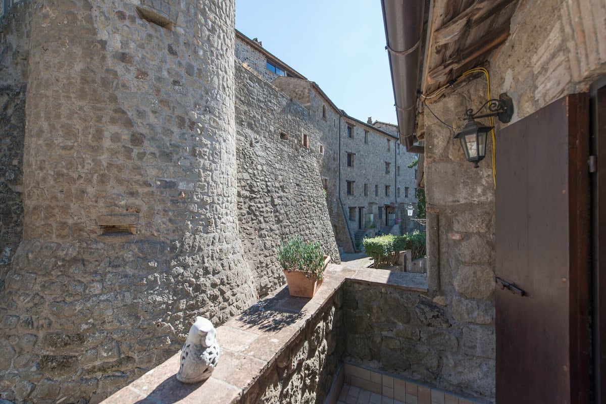 A narrow stone corridor with a potted plant and a stone statue.