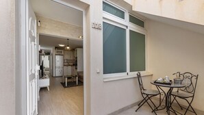 Un apartament compacte amb cuina americana, zona de dinar amb taula i cadires, i una finestra gran amb vistes.