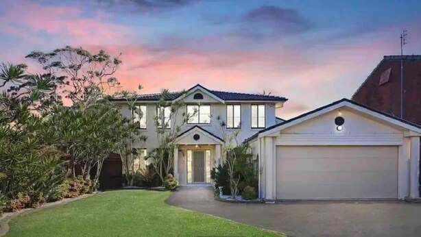 A two-story house with a garage, surrounded by well-maintained lawns and trees. - Large Holiday Home with Heated Pool on demand near Lake & Beaches (Lake Munmorah)