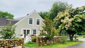 A two-story house with a stone wall and a porch.
