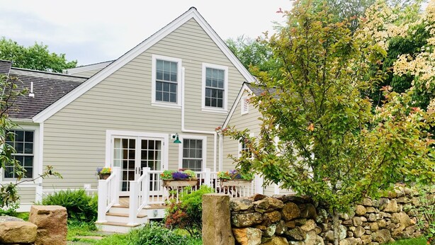A two-story house with a stone wall and a wooden deck.