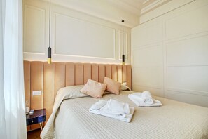 A hotel room with a large bed, a bedside table, and a wall-mounted light fixture.